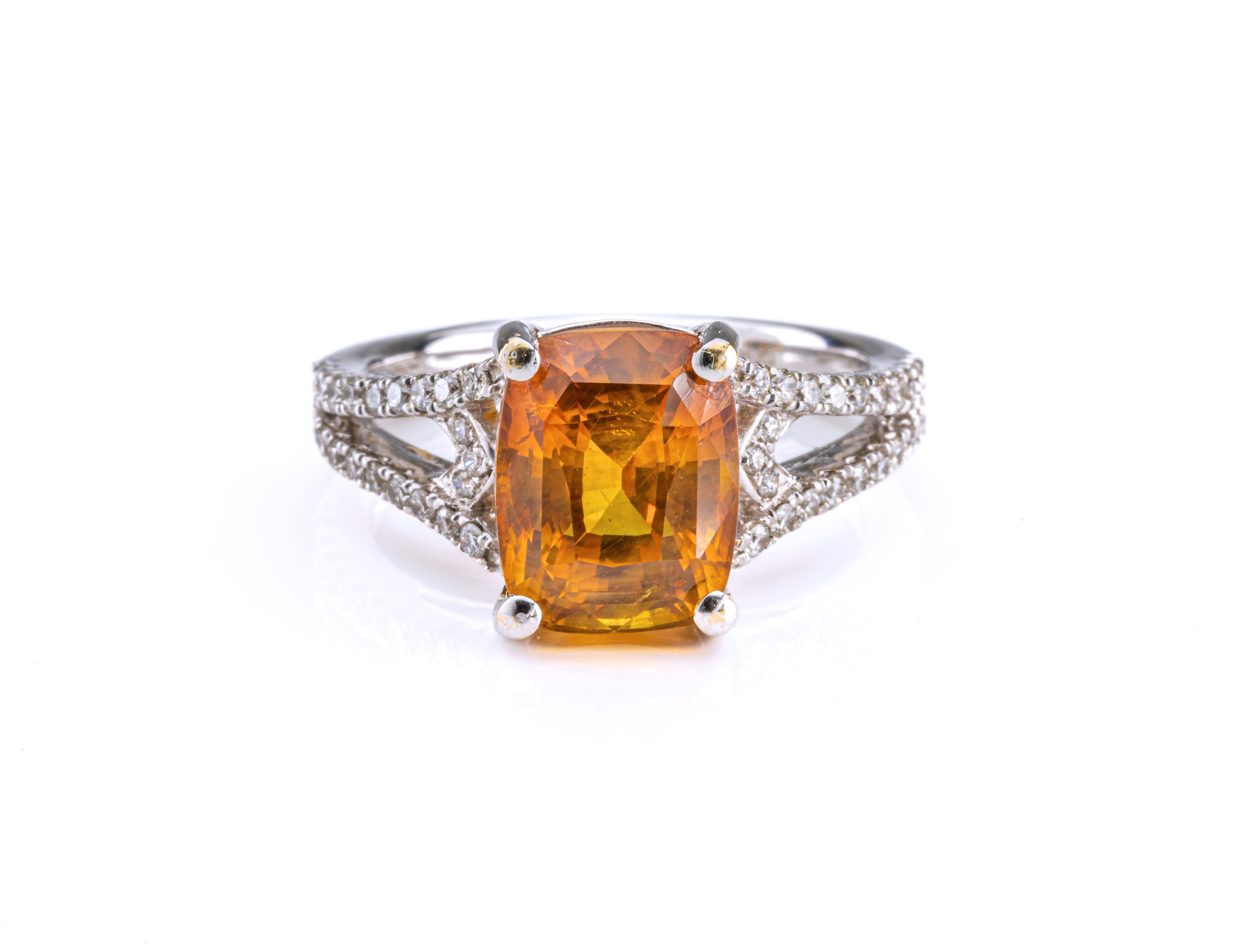 An 18ct white gold, yellow sapphire and diamond ring, set with a cushion-cut yellow sapphire,