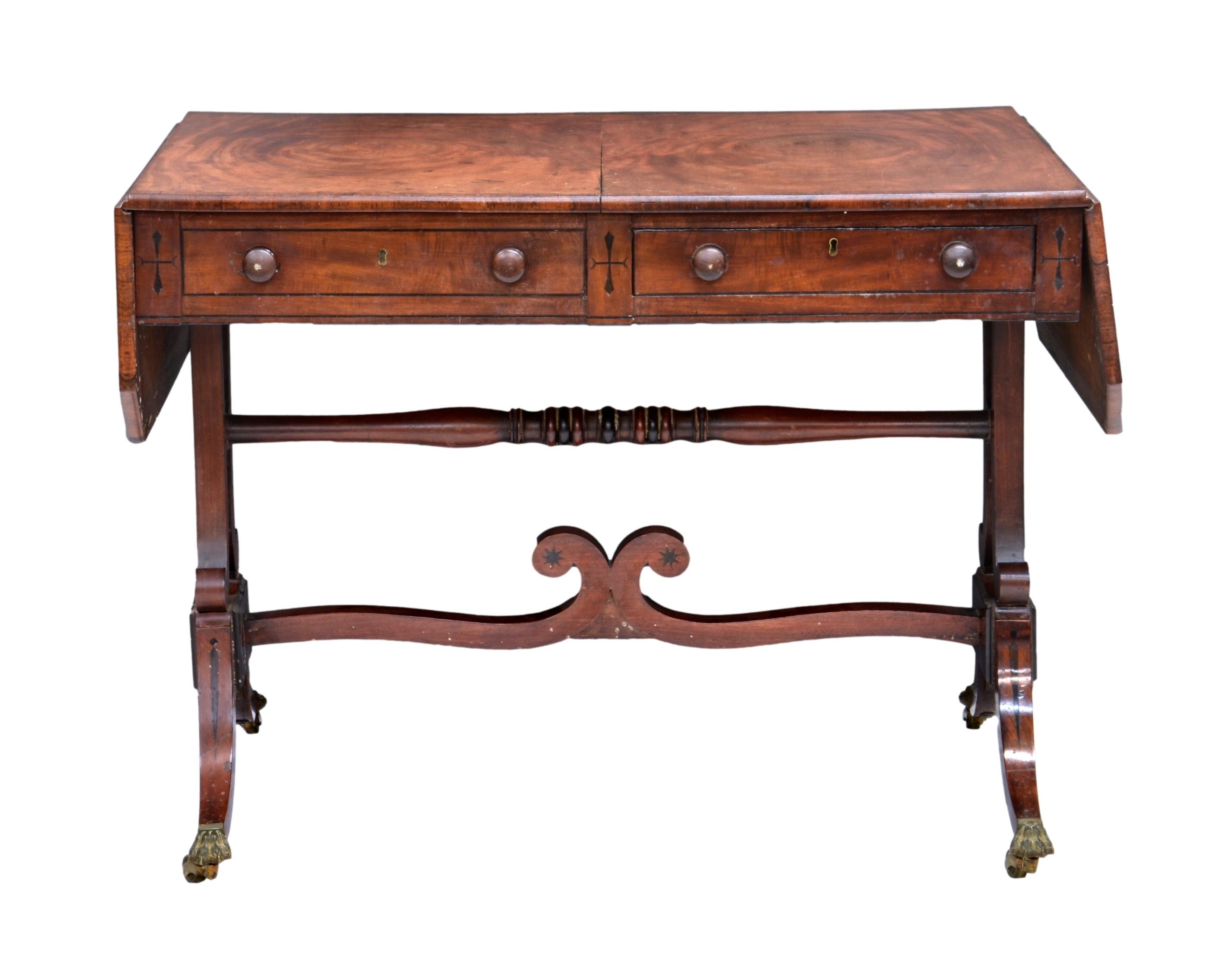 A Regency mahogany sofa table, the top with clipped corners, cross banded over two ebony strung