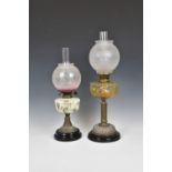 Two antique oil lamps, the first with bronze coloured moulded glass reservoir, depicting scrolls and