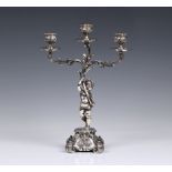 A Continental silver three branch figural candelabra, in the form of a cherub holding a three