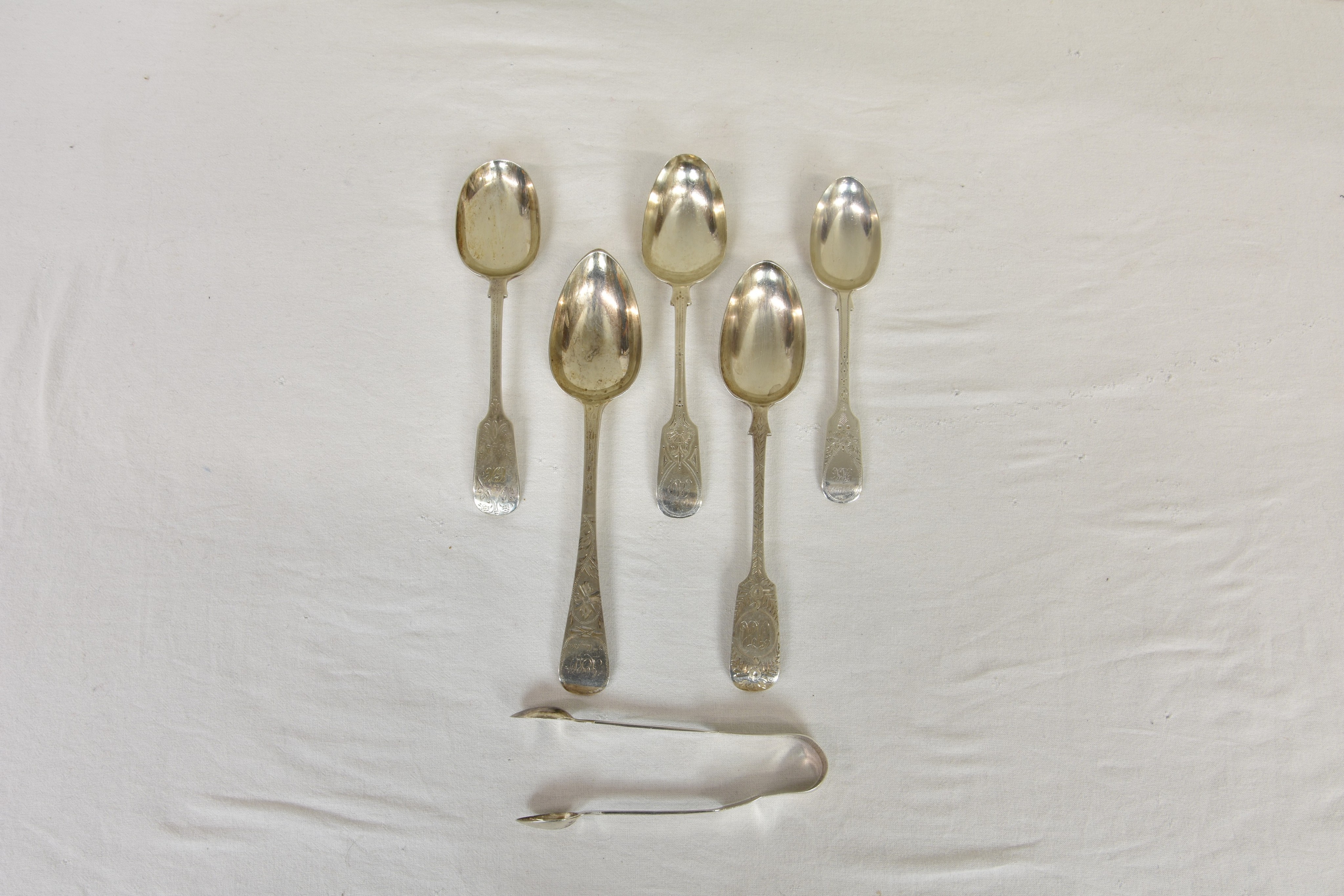 A collection of Channel Islands related silver spoons and sugar tongs, the tongs of typical form,