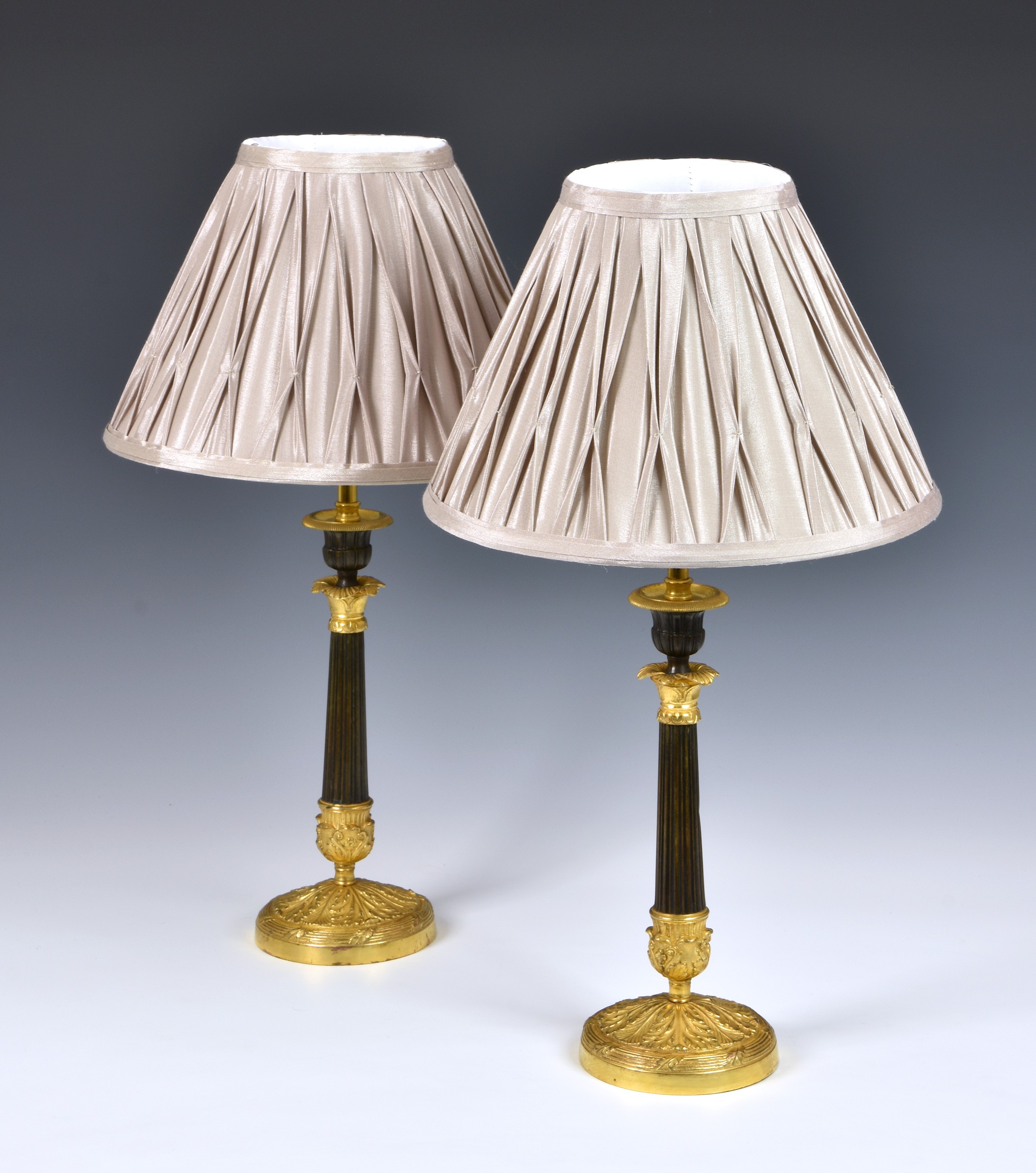 A pair of French patinated bronze and ormolu candlesticks, 19th century, the gadrooned urn sconces