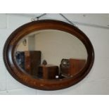 A large canted rectangular beaded oak wall mirror; an oval wall mirror in an inlaid mahogany frame.