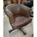 A swivel, tub shaped office arm chair in brown upholstery