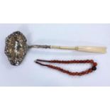 A amber coloured agate bead necklace and a whale bone and white metal handled punch ladle (a.f.)