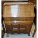 An oak Arts & Crafts bureau with cupboard enclosed by panelled door, 77 cm