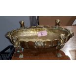 A brass oval serving dish with sun burst decoration on 4 lion's paw feet with lion's heads and 4