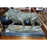 A bronze of a prowling lion an a black marble base, length 43cm.