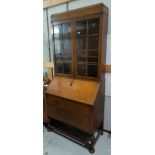 A 1930's oak bureau bookcase with double glazed doors above, one long and two short drawers with
