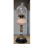 A Victorian oil lamp with brass collar and opaque pink reservoir