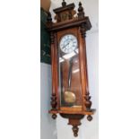 A 19th century Vienna wall clock in walnut case with carved pediment, half turned and reeded side