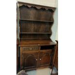 A reproduction oak welsh dresser with 2 height delft rack over 2 cupboards and 2 drawers