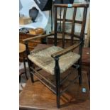 An Arts and Crafts style child's rush seat arm chair