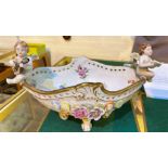 A Dresden style boat shaped bowl with cherub mounts and encrusted polychrome decoration, length 30cm