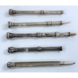 5 Edwardian chased white metal propelling pencils, with gem set terminals.