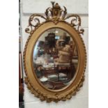 An oval wall mirror in period style gilt frame with scrolled rococo crest, height 90 cm