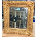 A rectangular bevelled edge wall mirror in ornate gilt frame