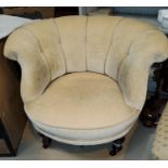 A Victorian low tub armchair on turned supports and castors, upholstered in cream fabric