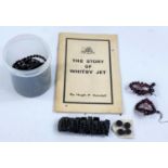 A selection of jet coloured jewellery and a pamphlet on the Story of Whitby Jet