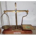 A 19th century brass balance scale on mahogany plinth with 5 graduating bell weights 10gm-100gm