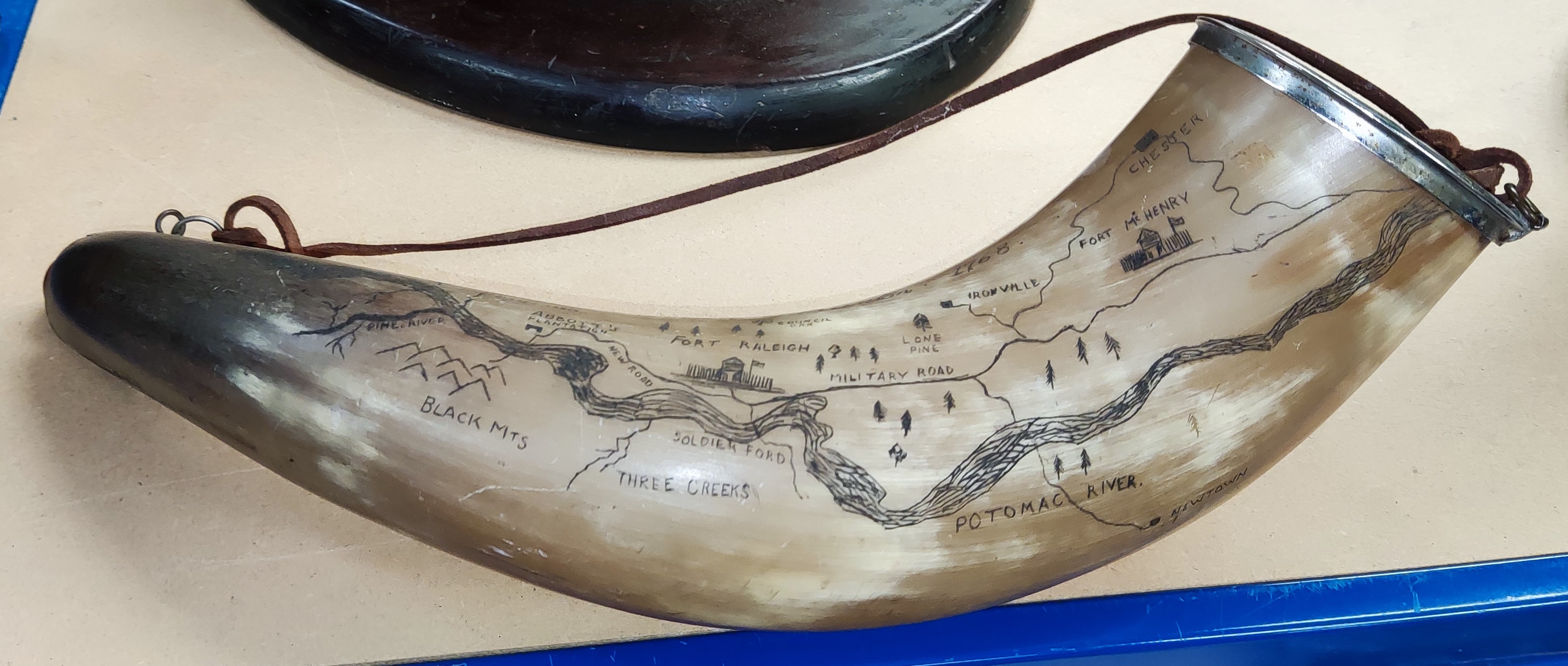 A Horn bearing a carving of a map, Fort Raleigh 1768. Length 37cm