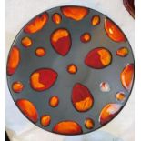 A large Poole Pottery plaque with black matt background, decorated with orange & red glazed spots,