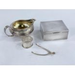 A hallmarked silver engine turned cigarette box, London 1918; an oriental white metal sauce boat;