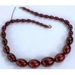 A string of 32 cherry amber bakelite graduating beads, from 1cm to 3cm, with internal streaking,