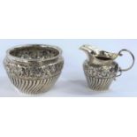 A matched set of a hallmarked silver sugar bowl and milk jug with ribbed decoration with flowers