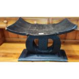 A late 19th/early 20th century African carved tribal stool with O shaped support with central carved