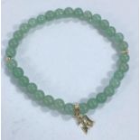A bracelet formed from celadon green jade coloured rounded beads with gold pendant attached, stamped