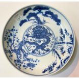 A Chinese blue and white dish with central dragon surrounded by trees six character mark to base