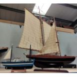 Two wooden model yachts, the larger in full sail