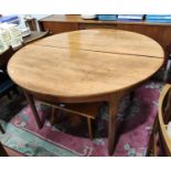 A 1960's teak dining table with circular extending top, 1 spare leaf