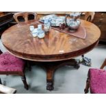 An early 19th century figured mahogany supper table with circular tilt top, on turned and carved