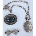 A white metal locket with incised decoration and similar chain, a white metal brooch with central