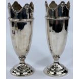 A pair of hallmarked silver vases with weighted bases, tapering form with peaked shell rim,