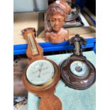 A carved aneroid barometer, another carved wooden South East Asian bust