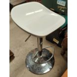 A modern chrome and white bar stool with rise and fall action