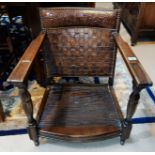 A 1930's oak very low seat armchair with studded woven leather back and grape and vine top rail/