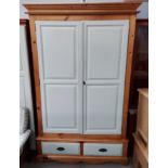 A double door wardrobe with base drawer in part pine/cream finish