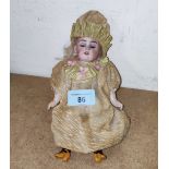 A small bisque head doll with composition body and limbs in Victorian dress