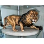 A ceramic male lion on marble base