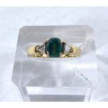 An 18 carat hallmarked gold ring set central oval emerald (6mm long approx) and 2 triangular