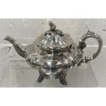 A hallmarked silver teapot with embossed and relief decoration, with acorn finial, leg decoration