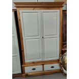 A double door wardrobe with base drawer in part pine/cream finish