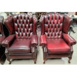 A pair of wing back armchairs in deeply buttoned oxblood hide