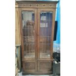 A 1930's oak full height side cabinet with twin leaded glass doors over twin panelled doors