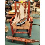 A 19th century child's spindle back rocking chair with raffia seat, a model ship and a Maori boat