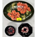 A Moorcroft Hibiscus oval dish and two dark blue Moorcroft trinket dishes with magnolias.